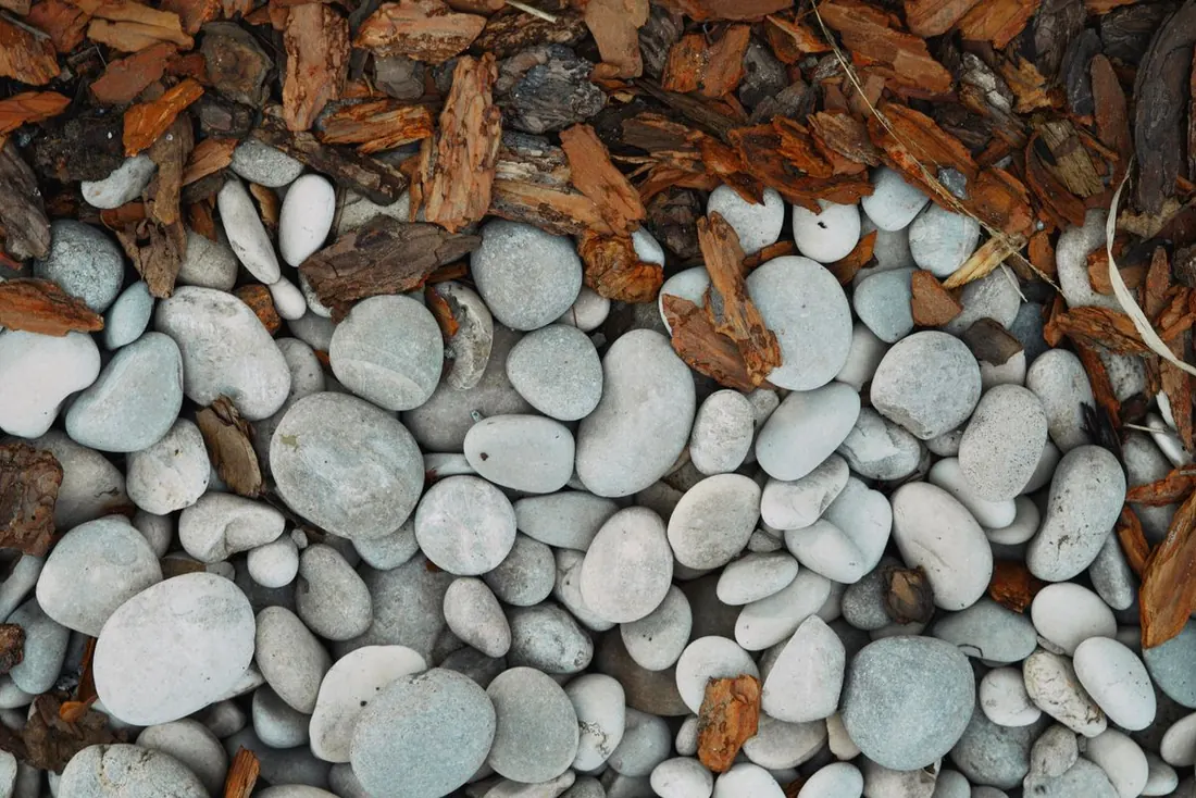Mulch and rock installation in Kelowna, bark mulch beside smooth landscape stones